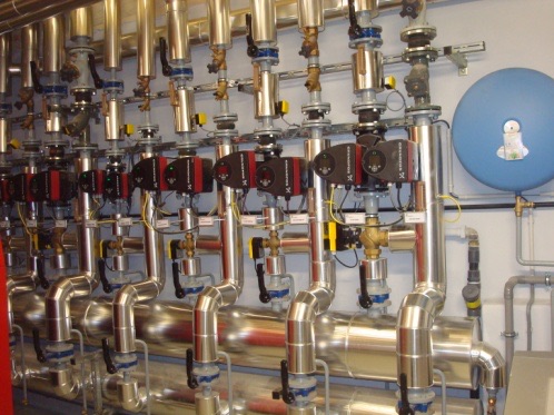 Sous-station hydraulique : collecteurs inox, circulateurs et vannes de réglage d'une installation de chauffage collectif.